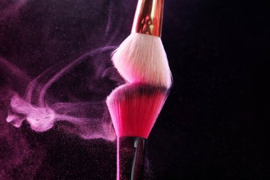Siyah arka planda pembe göz farlı makyaj fırçaları, yakın plan