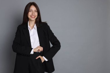 Gri arka planda takım elbiseli mutlu kadın, mesaj için boşluk