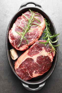 Çiğ et parçaları ve baharatlar gri desenli masa üzerinde fırın kabında, üst görünüm