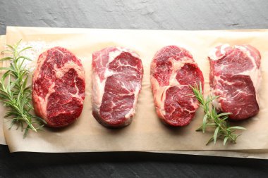 Çiğ et parçaları ve baharatlar siyah masada, üst görünümde.