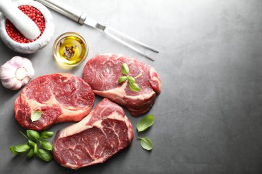 Çiğ et, baharat ve çatal parçaları gri masada, düz yerde. Metin için boşluk