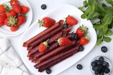 Lezzetli meyve dürümleri, çilekler, yaban mersinleri ve nane şekeri beyaz fayanslı masa, düz yatak