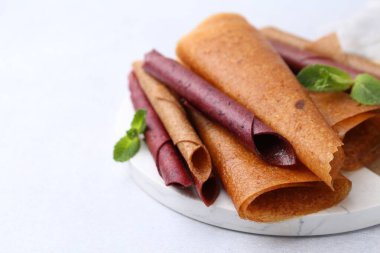 Lezzetli meyve dürümleri ve nane şekeri ışık masasında, yakın plan. Metin için boşluk