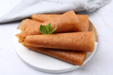 Lezzetli meyve dürümleri ve nane şekeri beyaz masada, yakın plan.