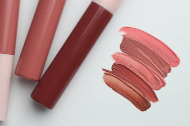 Beyaz arkaplanda renkli dudak parlatıcıları, düz yatış