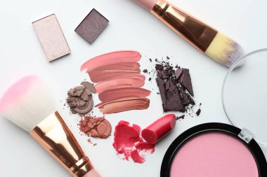 Beyaz arka planda farklı kozmetik ürünler ve makyaj fırçaları, düz yatış