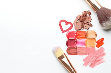Beyaz arka planda farklı kozmetik ürünler ve makyaj fırçaları. Metin için boşluk