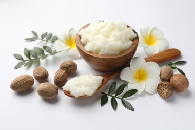 Shea yağı, fındık, plumeria çiçeği ve beyaz arka planda yapraklar