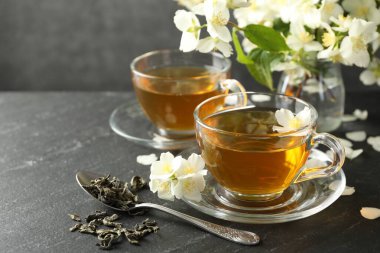 Aromatik yasemin çayı, bira ve çiçekler gri masada, yakın plan.