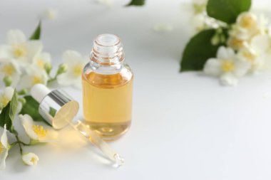 Temel yağ ve güzel yasemin çiçekleri beyaz masada, yakın plan. Metin için boşluk