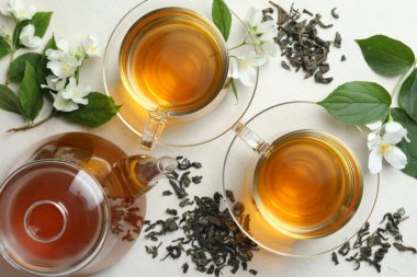 Cam fincanlarda, çiçeklerde ve yapraklarda beyaz masada yassı yasemin çayı.