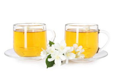 Cam fincanlar, çiçekler ve yeşil yapraklar içinde beyaz üzerine izole edilmiş yasemin çayı.