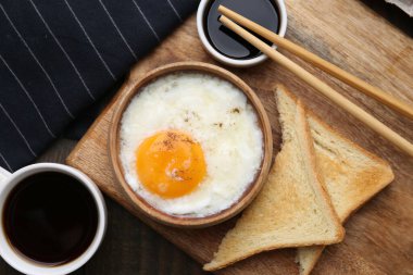 Tabakta yarı haşlanmış yumurta, soya sosu, yemek çubukları, kahve ve ahşap masada kızarmış ekmek, düz yatak. Geleneksel Asya kahvaltısı