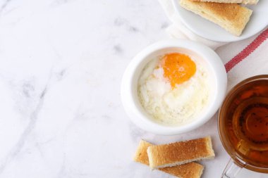 Yarı haşlanmış yumurta, çay ve kızarmış ekmek beyaz mermer masada, düz yerde. Geleneksel Asya kahvaltısı