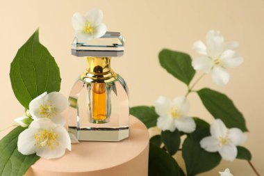 Bir şişe parfüm ve bej arka planda yasemin çiçekleri, yakın plan.