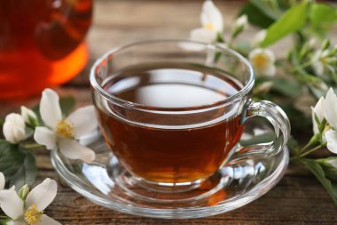 Lezzetli yasemin çayı fincanda ve çiçekler ahşap masada, yakın plan.