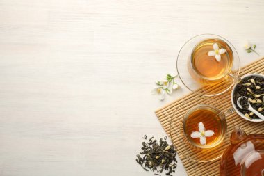 Lezzetli yasemin çayı fincanlar, çaydanlık, kuru yapraklar ve beyaz ahşap masa üzerinde çiçekler, düz yatak. Metin için boşluk