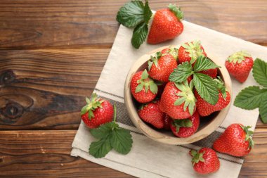 Taze olgun çilek ve yapraklar ahşap masada, düz yerde. Metin için boşluk