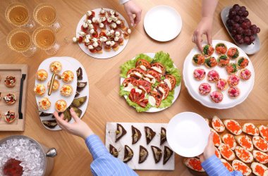 Açık büfe menüsü. İnsanlar ahşap masadan lezzetli aperatifler alıyor.