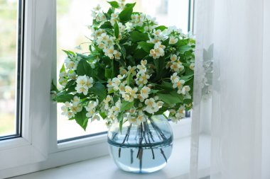 Güzel yasemin çiçekleri pencerenin yanındaki vazoda.