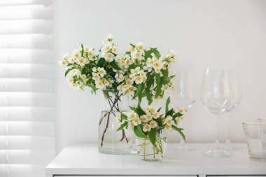 Güzel yasemin çiçekleri vazoda, beyaz masada.