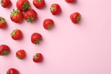 Açık pembe arka planda taze olgun çilekler, düz uzanış. Metin için boşluk