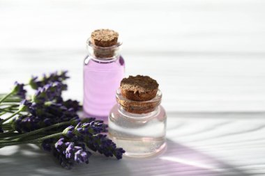 Beyaz ahşap masada doğal yağ ve lavanta çiçekleri, yakın plan.