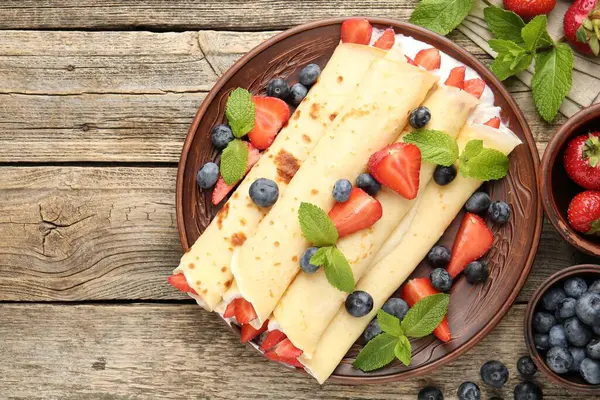 Böğürtlenli krep, krema ve nane şekerli ahşap masa, düz yatak. Metin için boşluk