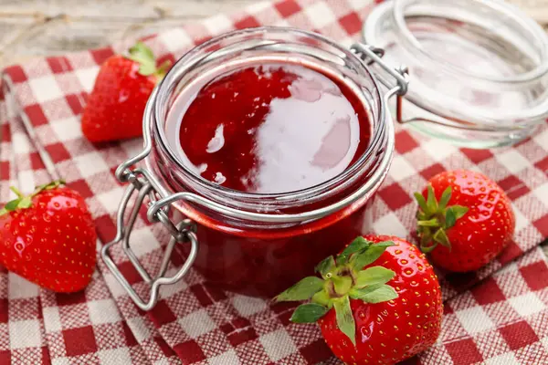Cam kavanozda lezzetli çilek reçeli ve masada taze böğürtlen, yakın plan.
