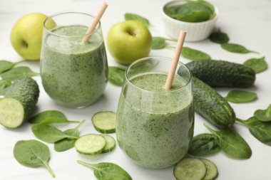 Lezzetli ıspanaklı smoothie ve malzemeler beyaz masada, yakın plan.