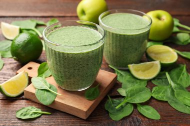 Lezzetli ıspanaklı smoothie ve ahşap masada malzemeler, yakın plan.