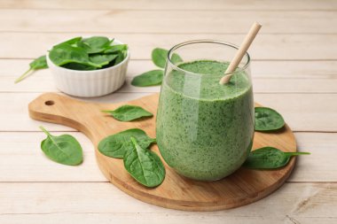 Lezzetli smoothie ve beyaz ahşap üzerinde ıspanak yaprakları