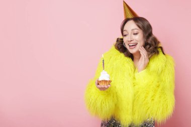 Doğum günü kutlaması. Pembe arka planda kek yiyen kadın. Metin için boşluk