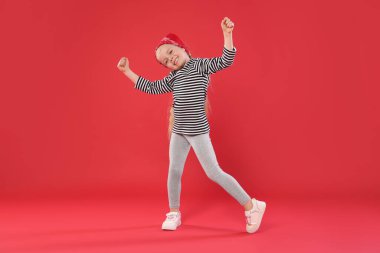 Kırmızı arka planda dans eden tatlı küçük kız.