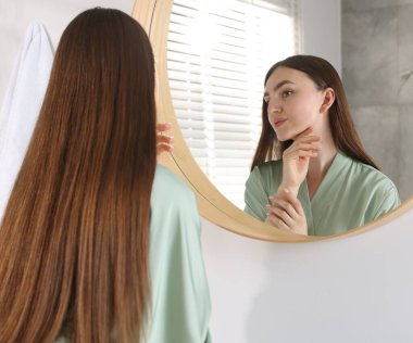 Güzel bir kadın aynada kendine bakıyor.