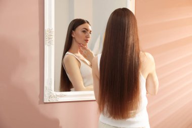 Güzel bir kadın aynada kendine bakıyor.