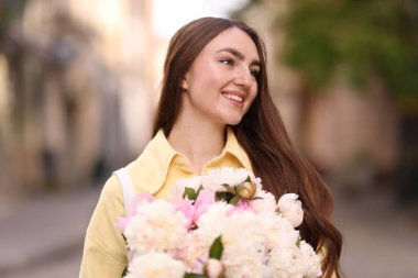 Şehir caddesinde elinde şakayık demeti olan bir kadın
