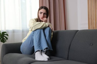 Evdeki koltukta paranoyadan muzdarip endişeli bir kadın.