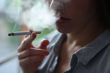 İçeride sigara içen bir kadın, yakın plan. Kötü alışkanlık.