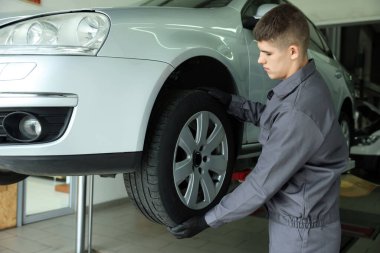 Araba servisinde lastik değiştiren profesyonel bir tamirci.