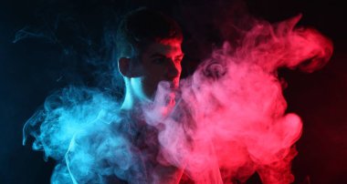 Koyu arkaplandaki neon ışıklarda elektronik sigara içen adam