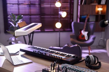 MIDI klavye, dizüstü bilgisayar ve kulaklıklar ev stüdyolarındaki ahşap masada.