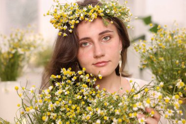 Kapalı alanda papatya çiçeği olan güzel bir kadının portresi.