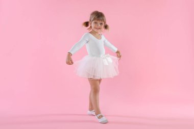 Pembe arka planda dans eden tatlı küçük kız.