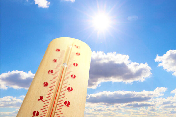 Высокая температура на термометре против неба в солнечный день