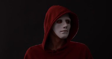 Anonimlik. Maskeli adam karanlık arka planda sessiz jest yapıyor.