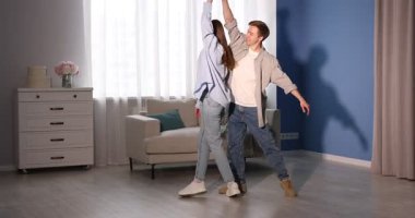 Mutlu genç çift evde dans ediyor.