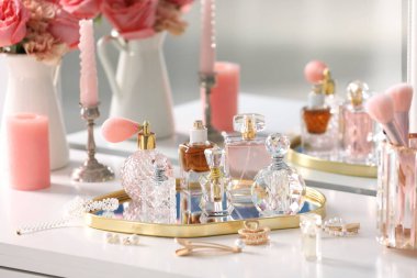 Farklı parfüm şişeleri, aksesuarlar ve çiçekler kapalı salonda.