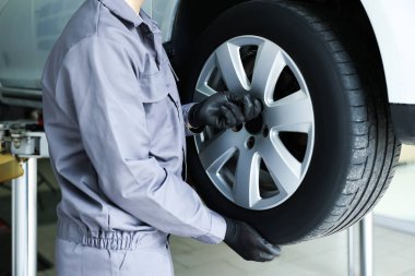 Tamirci araba servisinde lastik değiştiriyor, yakın plan.