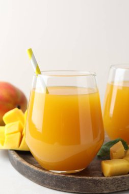 Bardakta lezzetli mango suyu ve beyaz masada taze meyve, yakın plan.